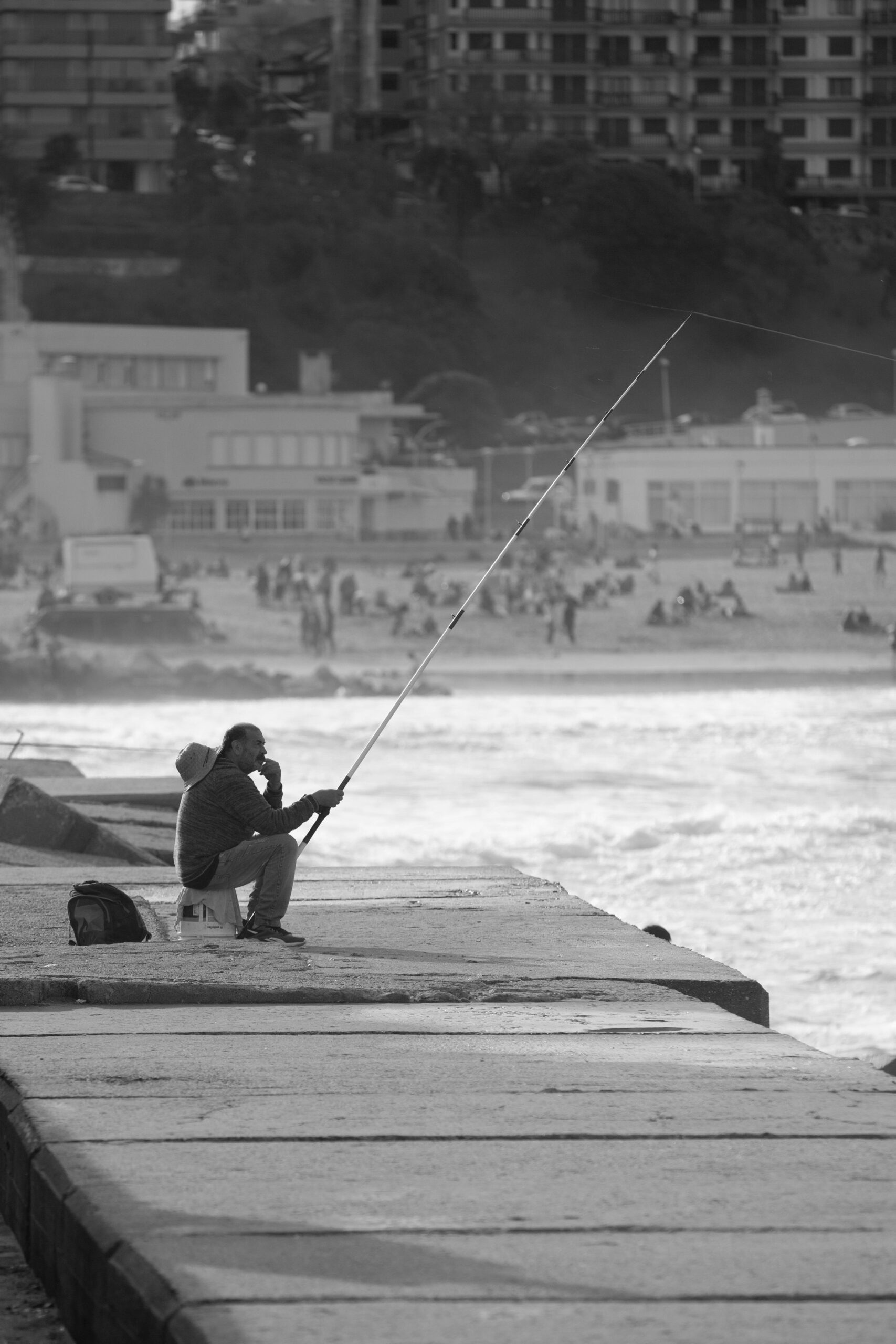 A solitary fisherman sitting by the waterfront in Mar del Plata, Argentina, casting a line into the sea.